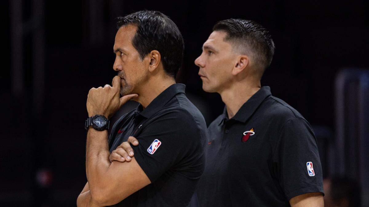 Miami Heat coach Erik Spoelstra and assistant coach Chris Quinn look on during the first half of an NBA preseason game against the San Antonio Spurs at Kaseya Center on October 8, 2025, in Miami.