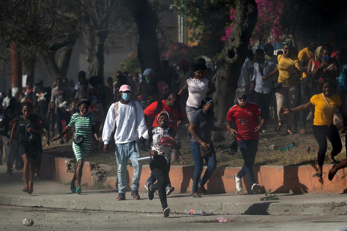 Factory workers run from tear gas fired by police trying to disperse their protest for salary increases in Port-au-Prince, Haiti, Wednesday, Feb. 23, 2022. It is the first day of a three-day strike organized by factory workers who also shut down an industrial park earlier this month to protest pay.