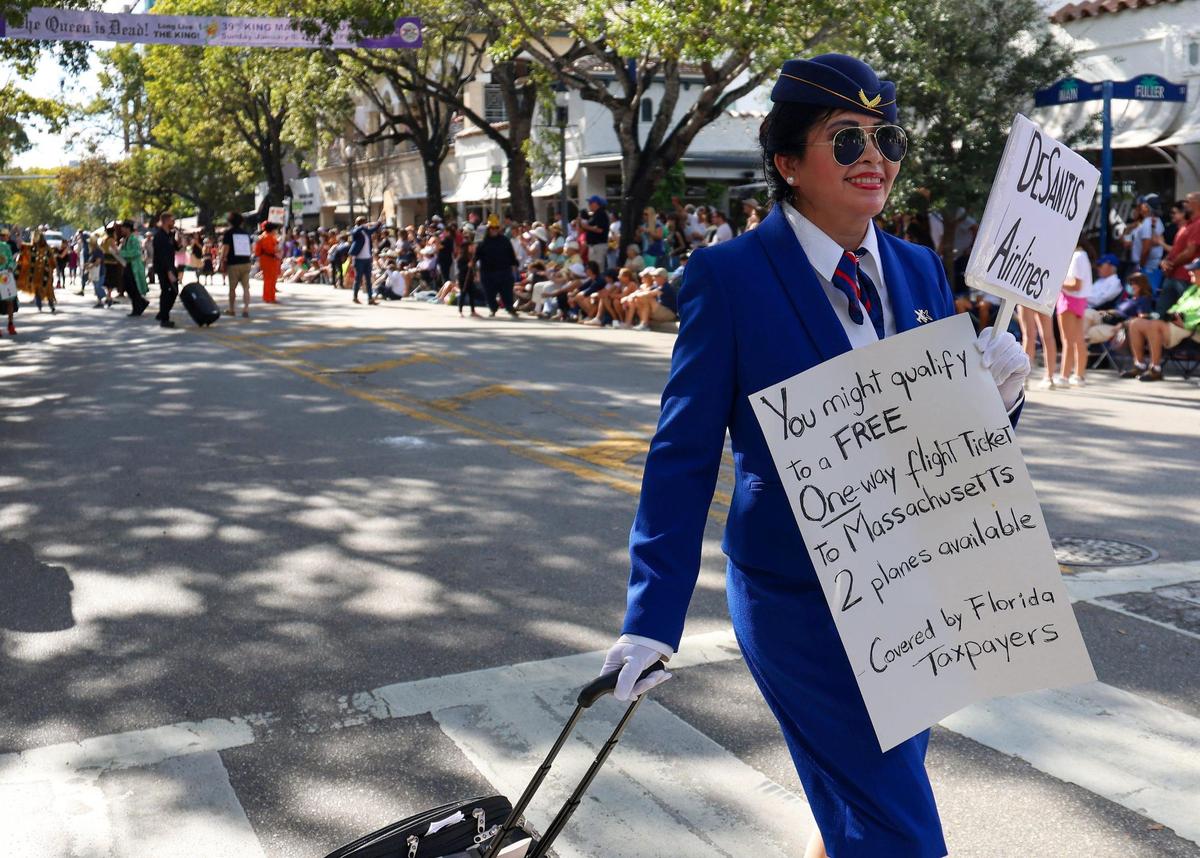 A parader mocks Gov. Ron DeSantis’ migrant flights as a flight attendant of DeSantis Airlines during the Annual King Mango Strut in Coconut Grove on Sunday, Jan. 8, 2023.