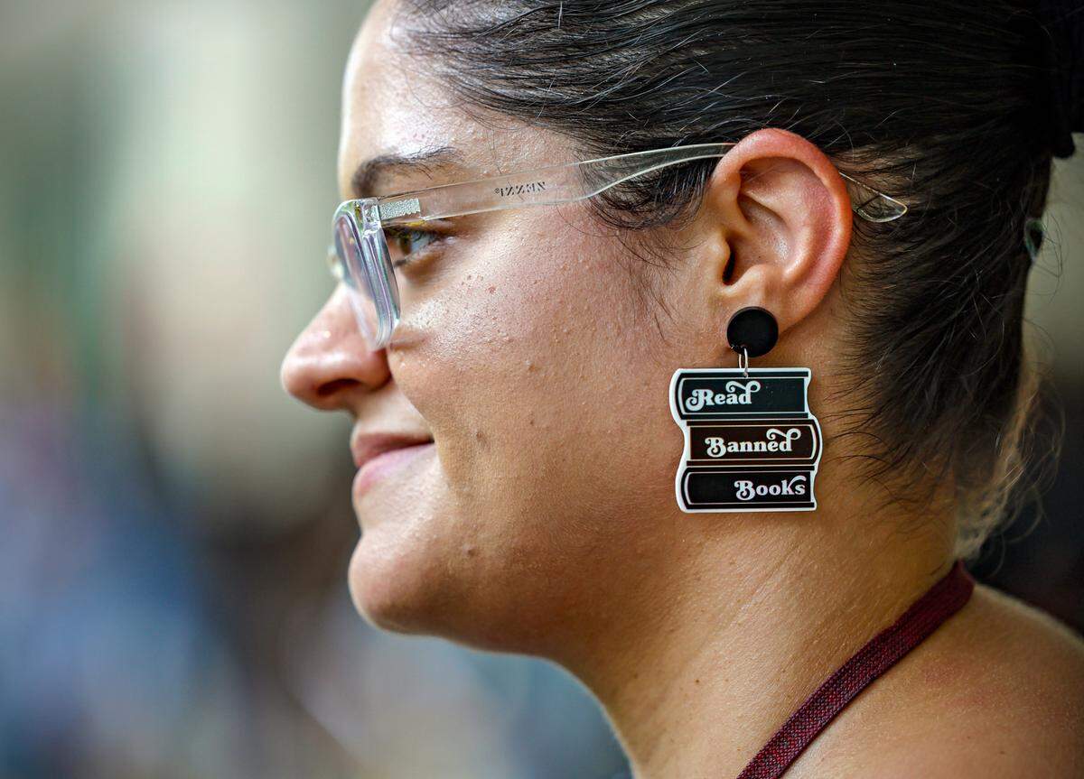 University of Miami staff member Amanda Valdespino wears earrings that says “Read Banned Books” as UM faculty hold a teach-in to raise awareness about two law proposals backed by Florida Governor Ron DeSantis that would affect higher ed, House Bill 999 and Senate Bill 266. Students and faculty gathered at Rock Plaza on campus in Coral Gables, Florida, on Tuesday, April 25, 2023.