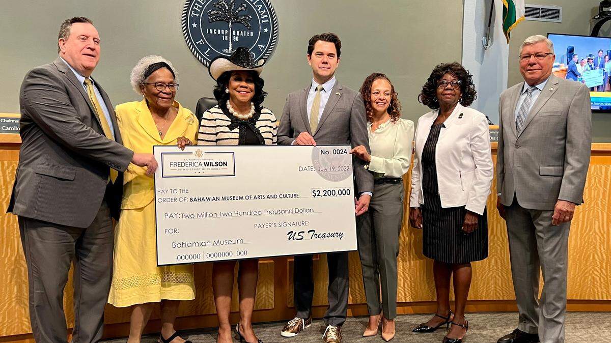 Comisionados de Miami posan con un cheque presentado por la representante federal Frederica Wilson, con sombrero, para conmemorar la asignación de $2.2 millones para un nuevo museo en Coconut Grove, el 19 de junio de 2022. El museo contará la historia de los colonos bahameños del Grove. De izquierda a derecha: el comisionado Joe Carollo, Thelma Gibson, Wilson, el comisionado Ken Russell, la comisionada Christine King, Dorothy Jenkins Fields y el comisionado Manolo Reyes. JOEY FLECHAS jflechas@miamiherald.com
