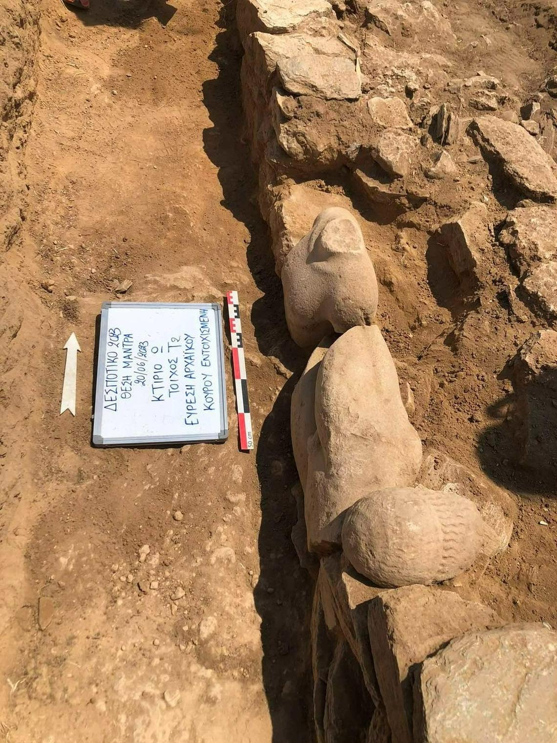 A wall by the temple entrance where fragmented statues — including a head and torso — were reused as building material.