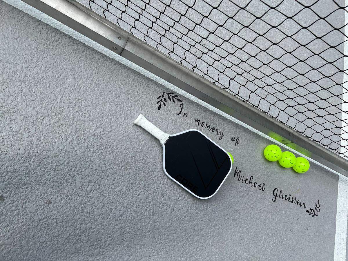On the pickleball court where Carolyn Glickstein teaches others how to play the sport is a written dedication to the memory of her son, Michael, who died in June 2021.