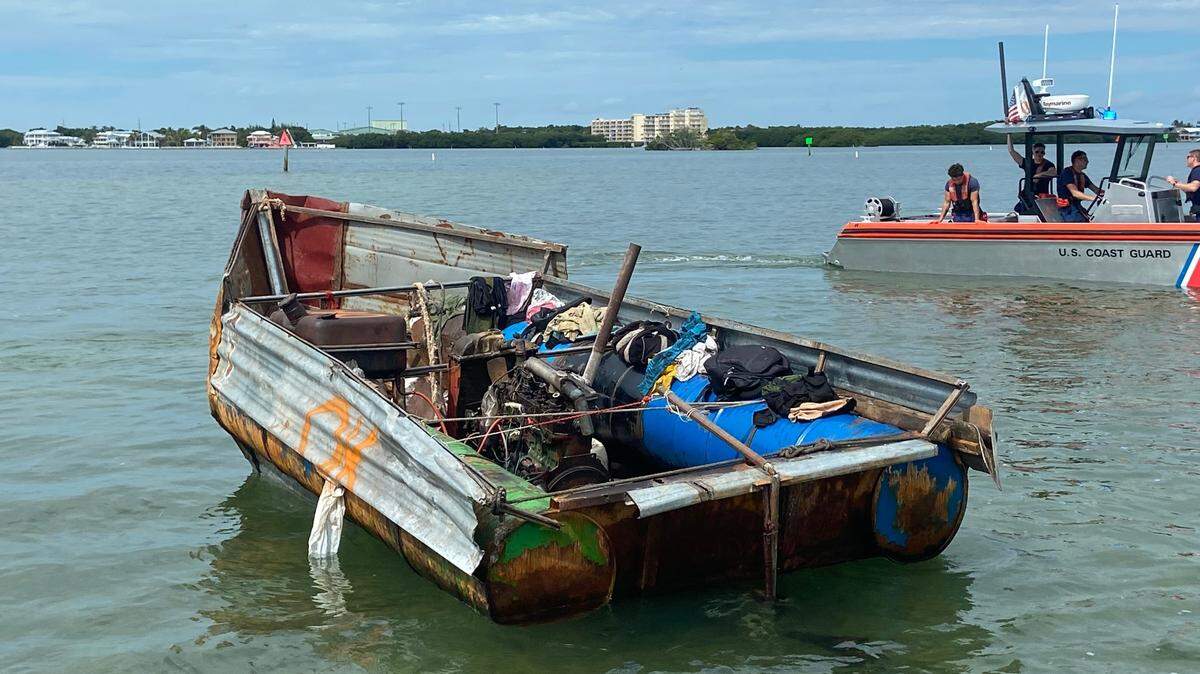 A U.S. Coast Guard boat approaches a Cuban migrant vessel on the ocean side of Tavernier Creek in the Florida Keys Friday, Oct. 14, 2022. The vessel had a hull made from welded together 50-gallon fuel drums and highway guard rails. It was powered by a Russian-built diesel engine.