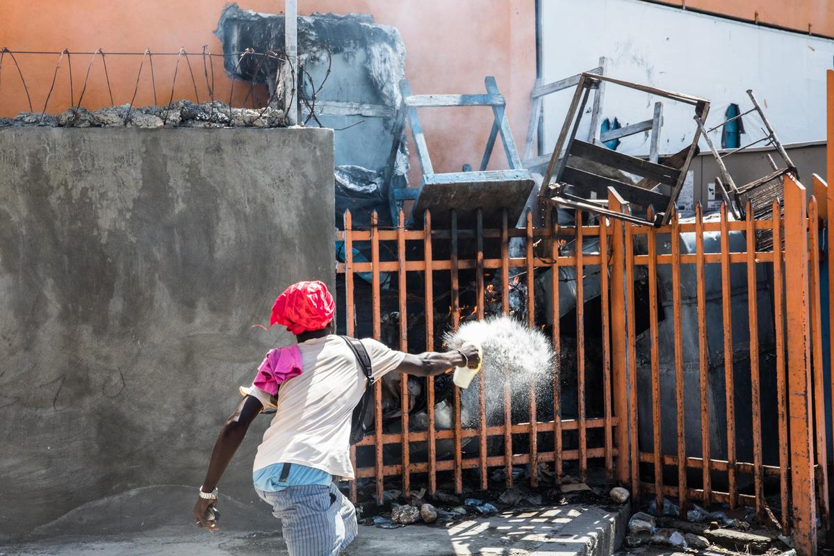 A man throws fuel on a fire as protesters, medical professionals, and political opponents demonstrate, demanding the resignation of President Jovenel Moise in the Haitian capital in Port-au-Prince on Oct. 30, 2019.