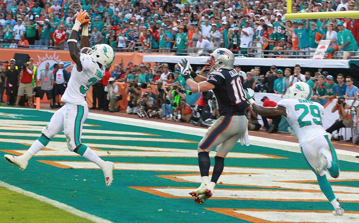 Miami Dolphin’s Michael Thomas intercepts a New England Patriots’ Tom Brady pass intended for Austin Collie in the final seconds of the fourth quarter to help the Dolphins win at Sun Life Stadium in Miami Gardens, Florida, December 15, 2013.