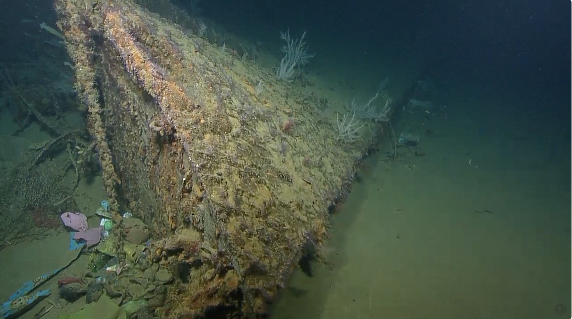 This nearly 100-foot long piece of debris was found with trash, including plastic bottles, piled up against it by the current.