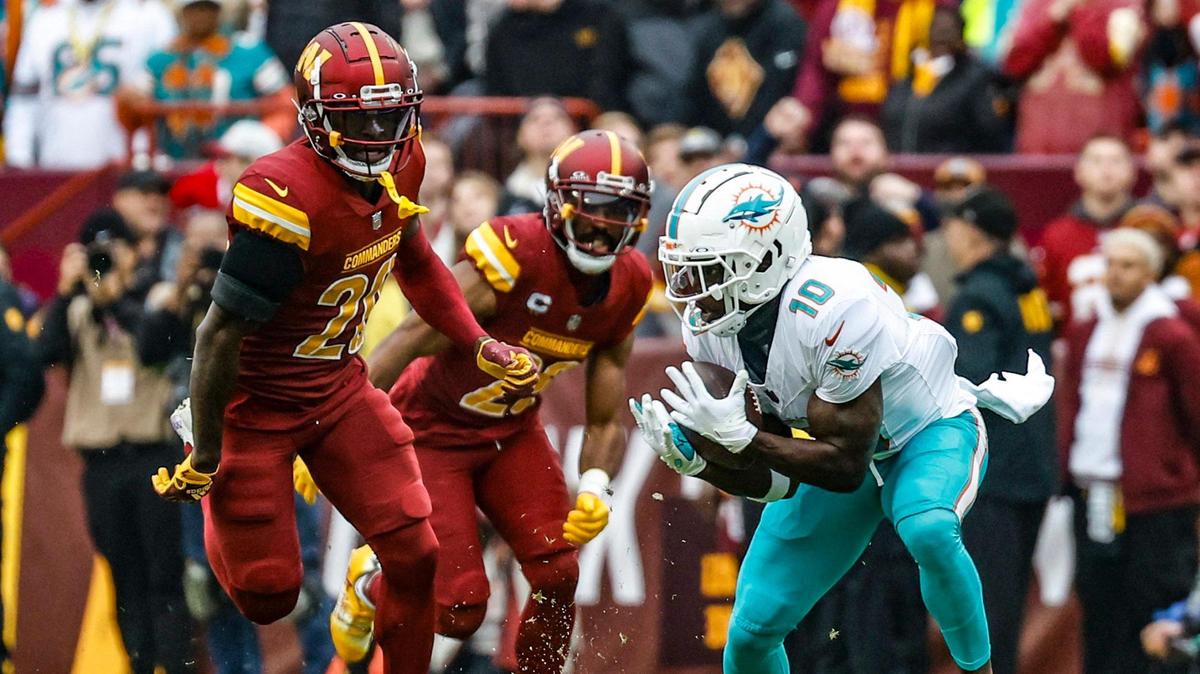 Miami Dolphins wide receiver Tyreek Hill (10) catches a touchdown pass as Washington Commanders safety Jartavius Martin (20) gives chase in the first quarter at FedEx Field in Landover, Maryland on Sunday, December 3, 2023.