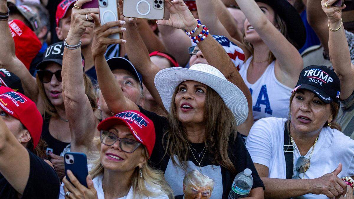 Los partidarios de Trump, muchos de ellos hispanos, intentan obtener videos del expresidente Donald Trump hablando durante un mitin en el Trump National el martes 9 de julio de 2024, en Doral.
