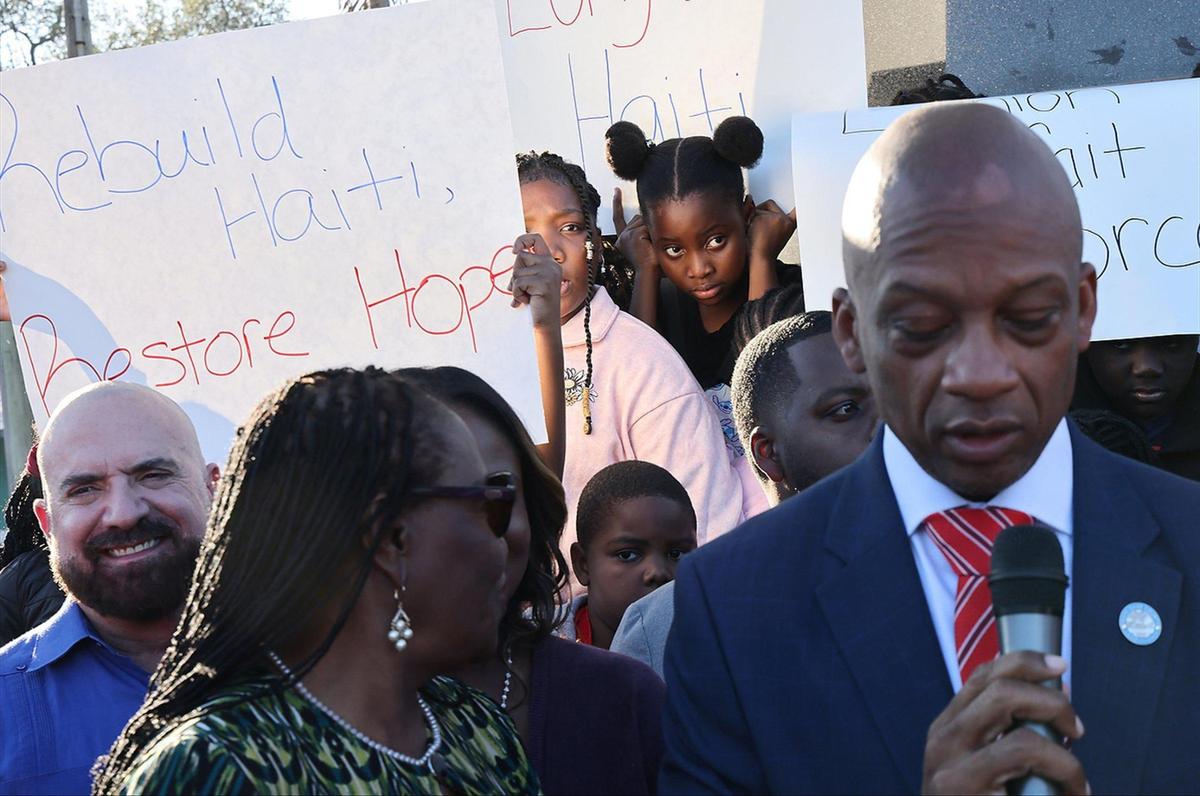 Miami-Dade Commissioner Oliver Gilbert, right, gives his remarks as members of the Haitian community and others gathered at Toussaint L’ Ouverture Statue for the customary moment of silence occurring at 4:53PM – the time of the 2010 earthquake prior to leading a procession to the Little Haiti Cultural Complex for a ceremonial remembrance of those who perished on Sunday, December 12, 2025.