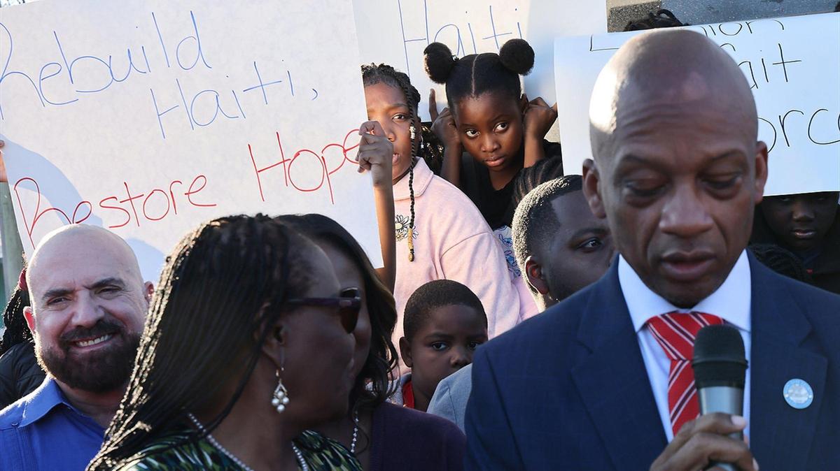 Miami-Dade Commissioner Oliver Gilbert, right, gives his remarks as members of the Haitian community and others gathered at Toussaint L’ Ouverture Statue for the customary moment of silence occurring at 4:53PM – the time of the 2010 earthquake prior to leading a procession to the Little Haiti Cultural Complex for a ceremonial remembrance of those who perished on Sunday, December 12, 2025.