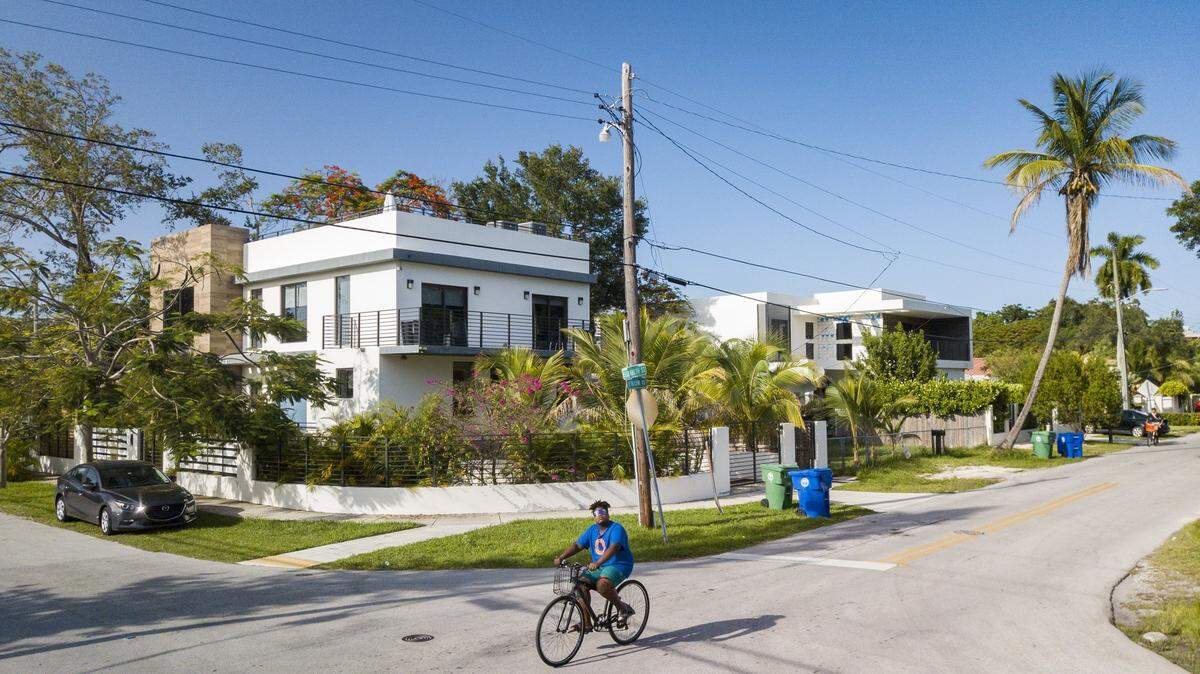 A resident of Miami’s historically Black West Coconut Grove cycles down what was until recently a street of modest working-class homes at the intersection of Elizabeth Street and Frow Avenue on Thursday, June 16, 2022. The mostly low-income West Grove community is disappearing amid the construction of multimillion-dollar “white cubes” that are sold to mostly white affluent buyers.