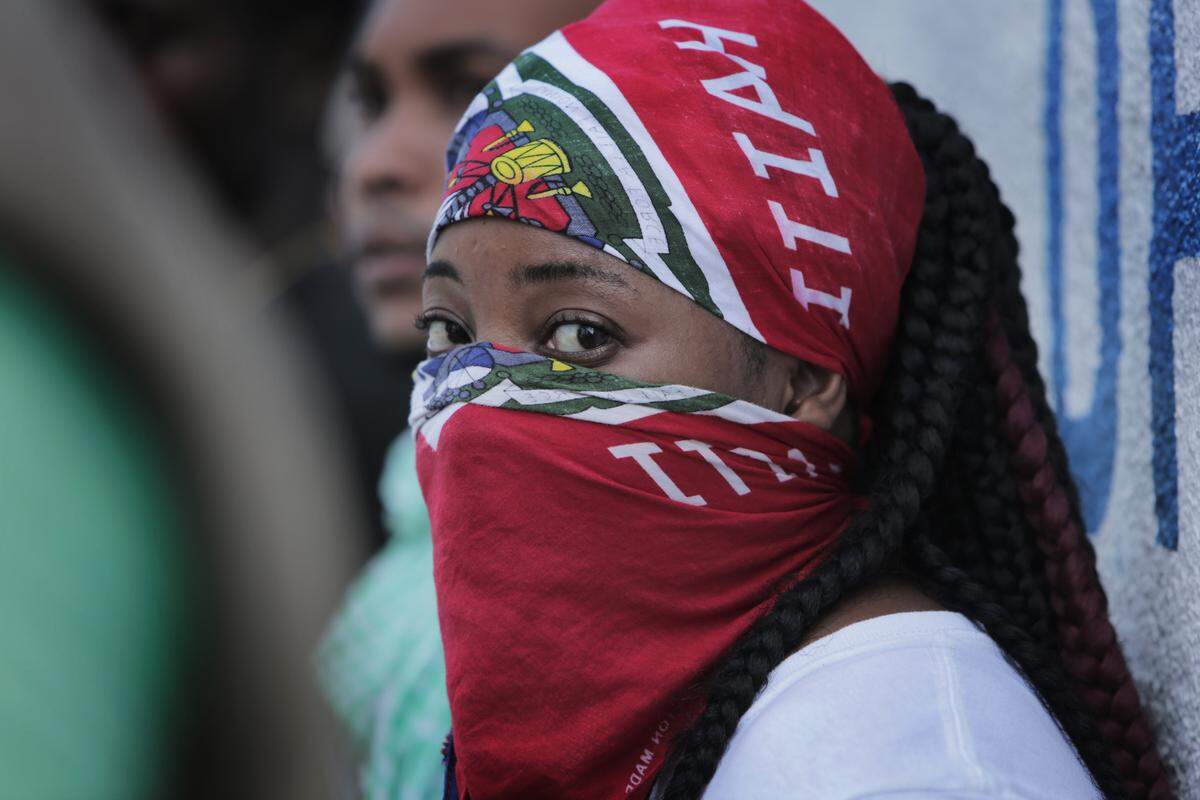 A young woman conceals her identity during a protest in front of Haiti National Police headquarters in Port-au-Prince on Nov. 17, 2019. Officers of the Haitian National Police took to the streets demanding better working conditions and a union to protect their rights.