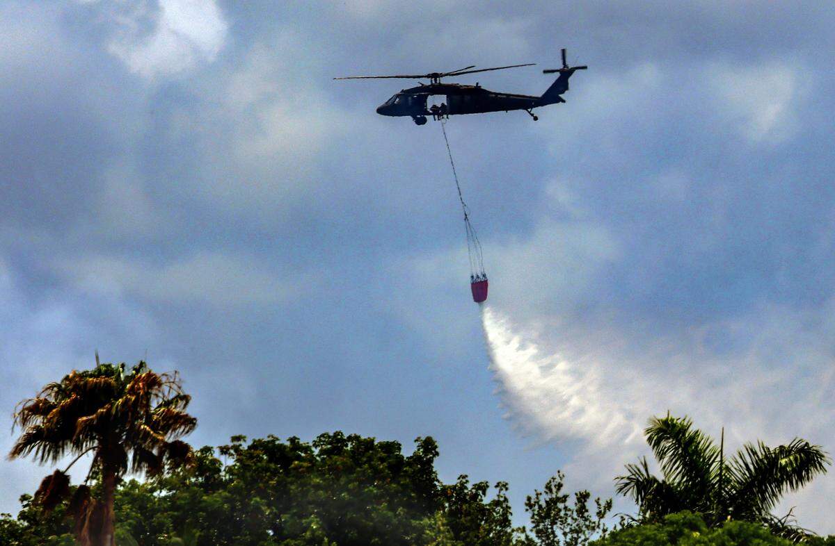 Florida Forest Service personnel monitor a wildfire just west of U.S. 1 and SW 344th Street while battling the blaze with helicopter water drops and ground crews on Monday, May 11, 2026, in Florida City, Fla.