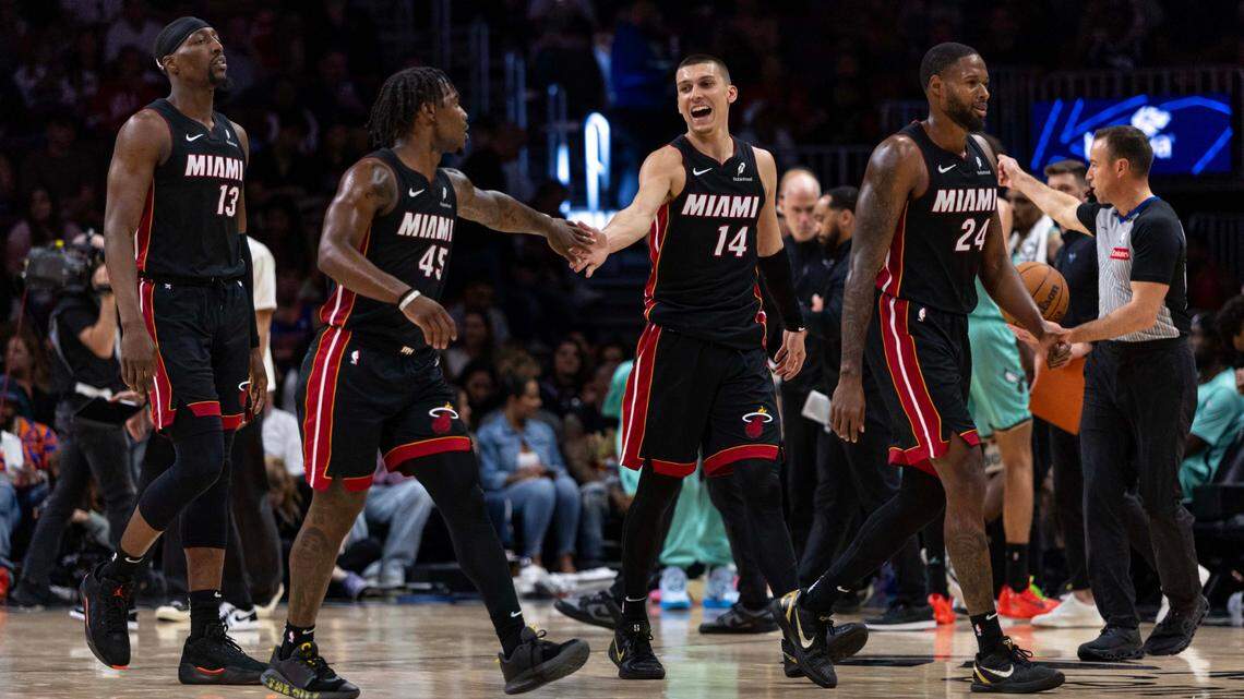 Miami Heat guard Tyler Herro (14) reacts with guard Davion Mitchell (45) during the second half of an NBA game against the Charlotte Hornets at Kaseya Center on March 21, 2025, in Miami.