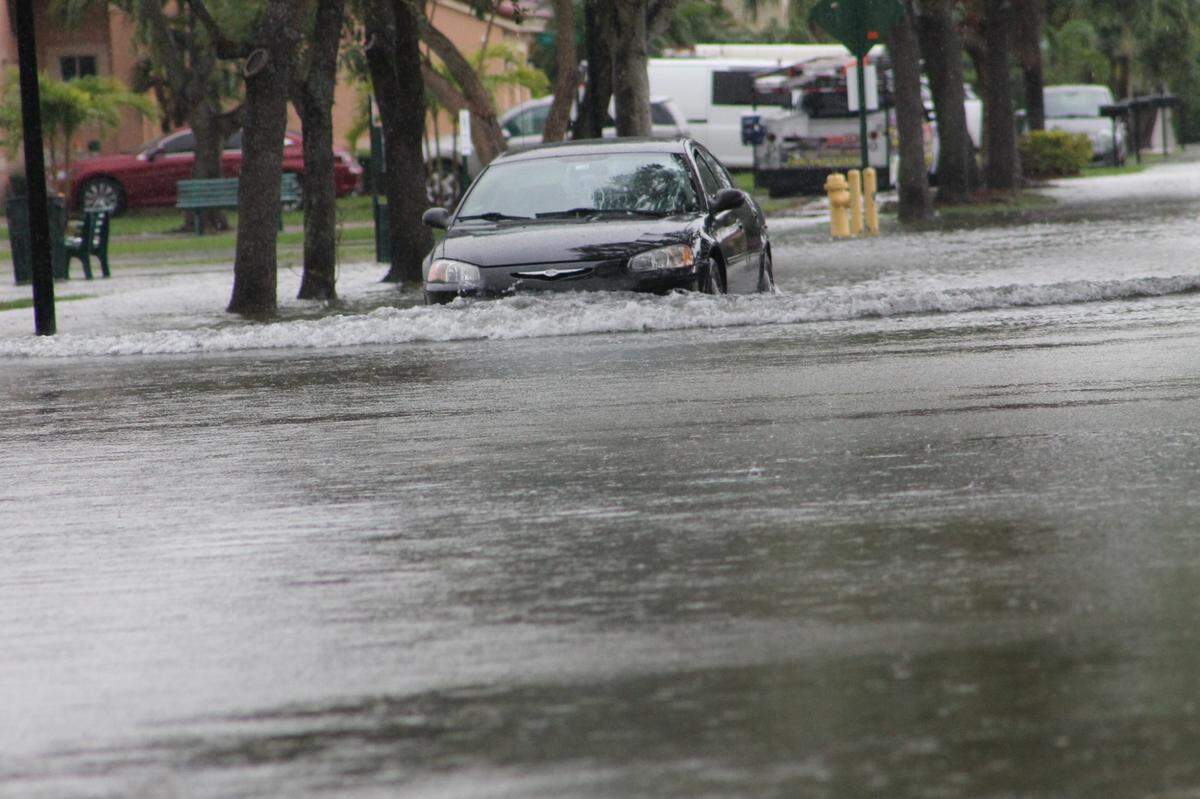 A car drives through a flooded roadway on Southwest 108th Place and 239th Street in South Miami-Dade in the afternoon of Thursday, June 9, 2022.