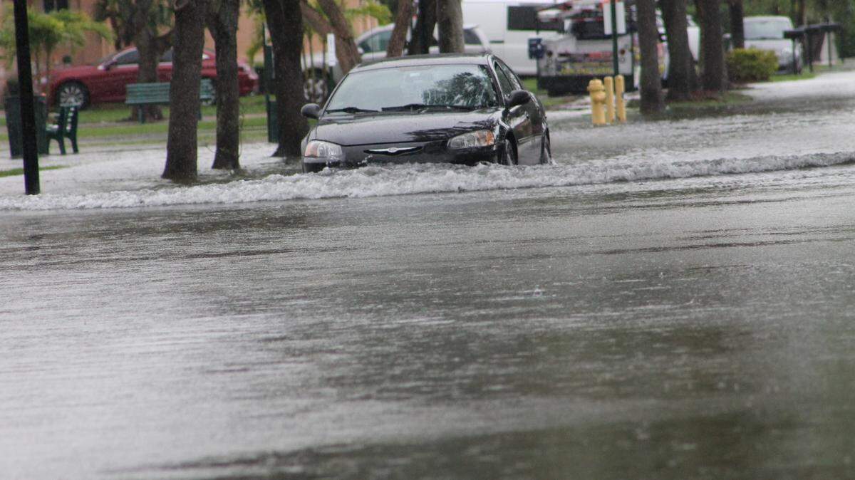 FILE: A car drives through a flooded roadway on Southwest 108th Place and 239th Street in South Miami-Dade in the afternoon of Thursday, June 9, 2022.