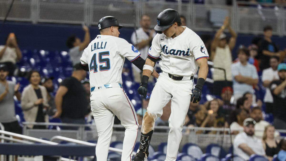 Miami Marlins left fielder Griffin Conine (18) and Miami Marlins third base coach Blake Lalli (45) celebrates Conine's  homer on a fly ball to right center field as Liam Hicks scores in the third inning against the Cincinnati Reds at loanDepot park in Miami, Florida, on Wednesday, April 8, 2026. 