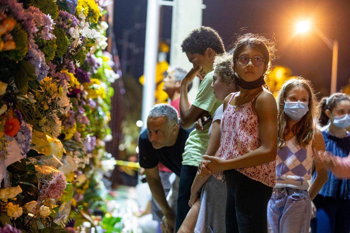 People of all ages pause and observe the makeshift memorial site located at Veterans Park for those missing and deceased after the partial collapse of Champlain Towers South in Surfside, Florida. They gathered the night a beach vigil was held, Monday, June 28, 2021.