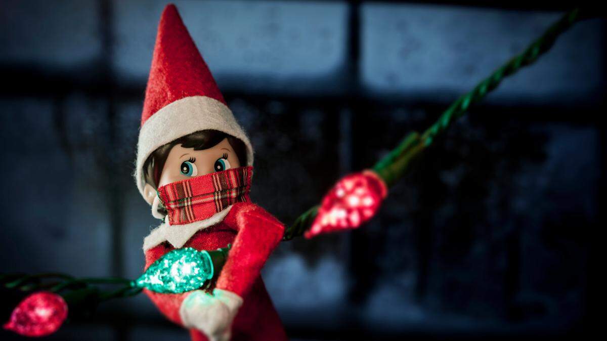 elf on the shelf hanging from christmas lights