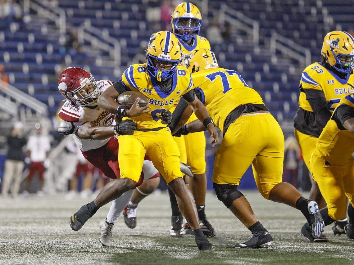 Miami Northwestern quarterback Neiman Lawrene (8) is taken down by Raines Vikings defensive end Cameron Washington (13) in the first half in Class 3A State Championship football game at FIU's Pitbull Stadium in Miami, Florida on Friday, December 12, 2025.