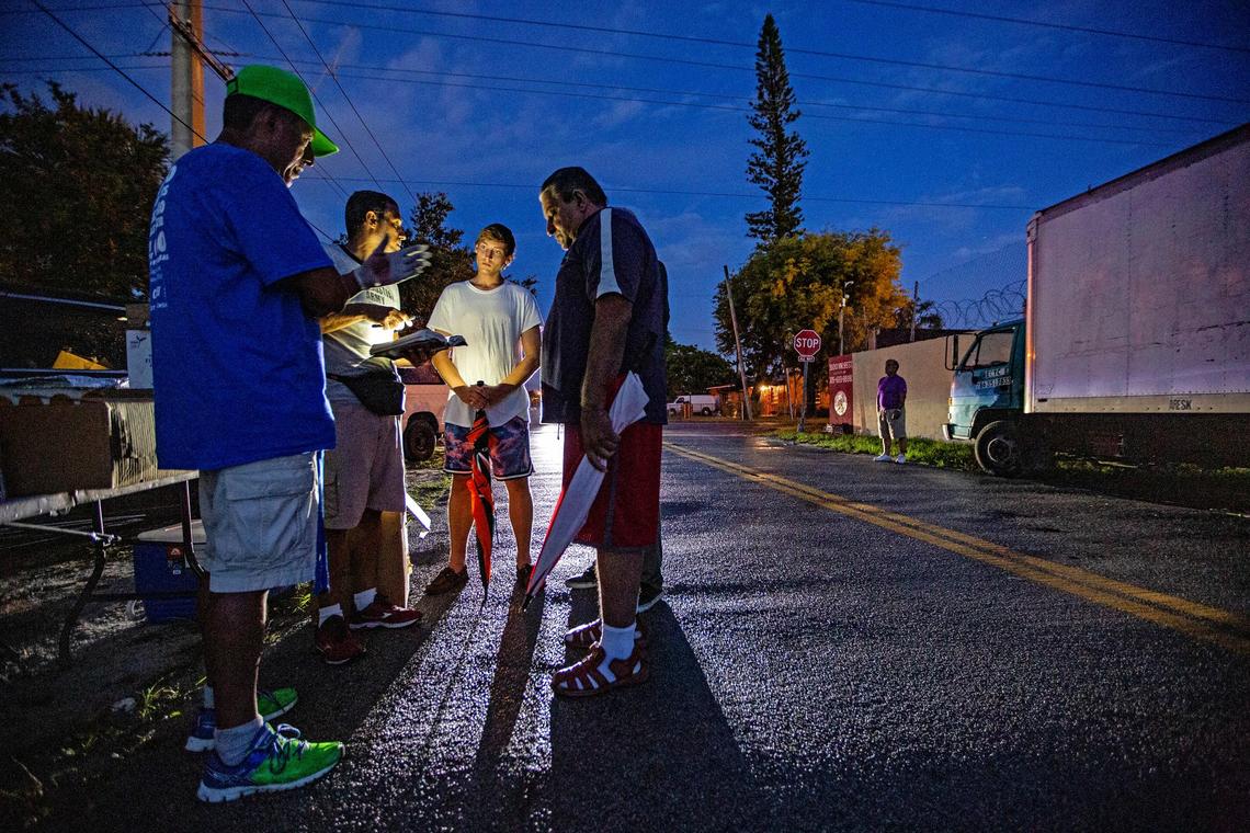 Pastor Frank Diaz, at left, of United We All Can Community Services, prays with volunteers and homeless convicted child sex offenders before distributing food at a tent city along Northwest 37th Avenue and 95th Street.