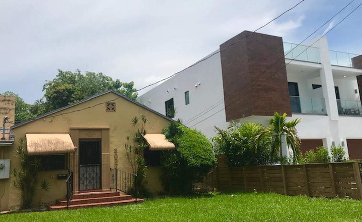 The contrast is jarring between an old house in West Coconut Grove and a new one that dwarfs it squeezed into the lot next door.