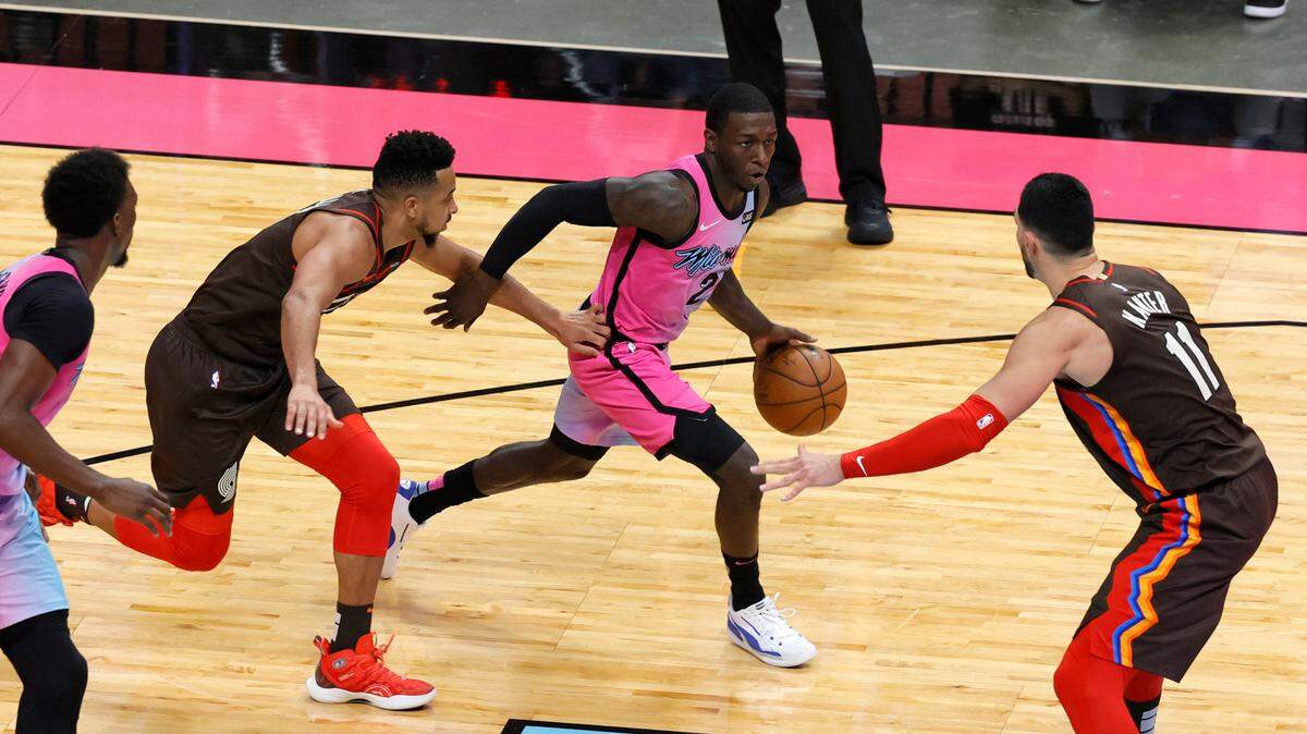 El base de los Miami Heat Kendrick Nunn (25) impulsa contra los jugadores de los Portland Trail Blazers CJ McCollum (3) y Enes Kanter (11) en el último cuarto de su partido de baloncesto de la NBA en el AmericanAirlines Arena el jueves 25 de marzo de 2021.