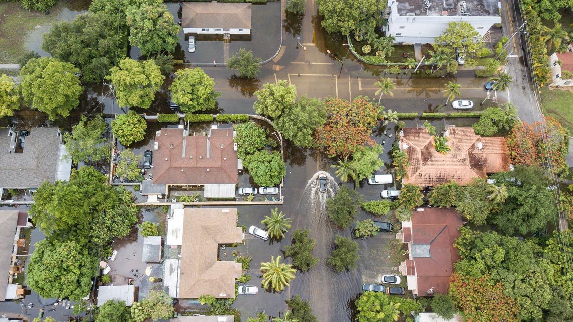 A vehicle travels along a flooded street in a residential area of North Miami, Florida, along Northeast 11th Avenue near Northeast 123rd Street on Thursday, June 13, 2024.