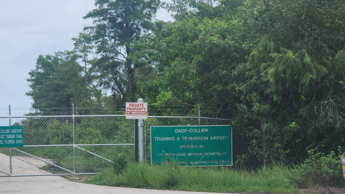 The bright blue sign that read ‘Alligator Alcatraz’ has been taken down and replaced with the original Dade-Collier Training and Transitional Airport sign and the gate is shut.