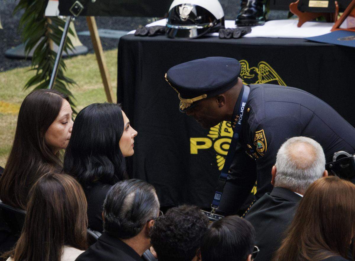 Police Chief Wayne Jones greets the wife of Miami Beach Police Sergeant David Cajuso during a funeral service for Cajuso on Wednesday, Nov. 12, 2025, at the Hard Rock Stadium in Miami Gardens, Fla.