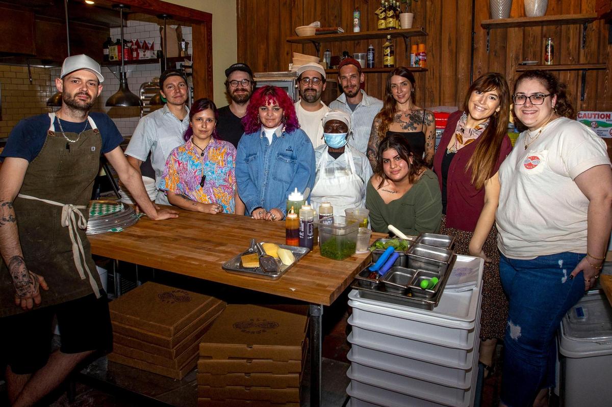 The staff gathers for a photo at Old Greg’s Pizza restaurant in Miami. The new establishment was rocked by building repairs, supply and staff shortages, and, of course, COVID-19.