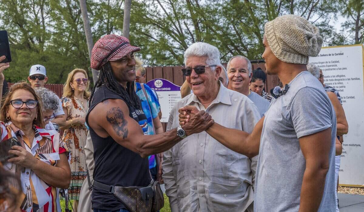 El artista Yotuel (izquierda) y el ex preso político cubano Ángel de Fana (centro) reciben al artista disidente cubano Luis Manuel Otero Alcántara en Our Lady of Charity National Shrine.