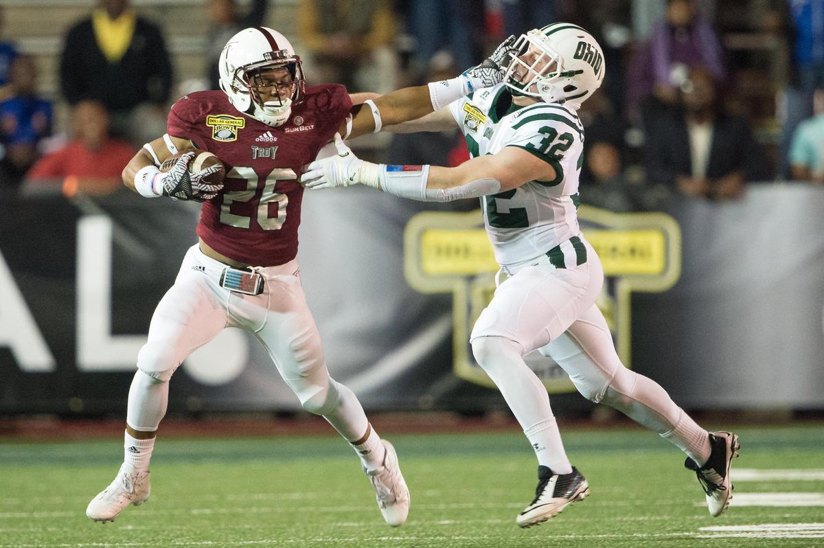 MOBILE, AL - DECEMBER 23: Running back B.J. Smith #26 of the Troy Trojans stiff arms linebacker Quentin Poling #32 of the Ohio Bobcats on December 23, 2016 in Mobile, Alabama.