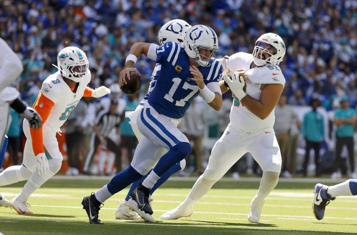Indianapolis Colts quarterback Daniel Jones (17) scrambles with the football as Miami Dolphins linebacker Matthew Judon (8) and defensive tackle Zach Sieler (92) close in during the first half of an NFL game at Lucas Oil Stadium on Sunday, September 7, 2025 Indianapolis, Indiana.