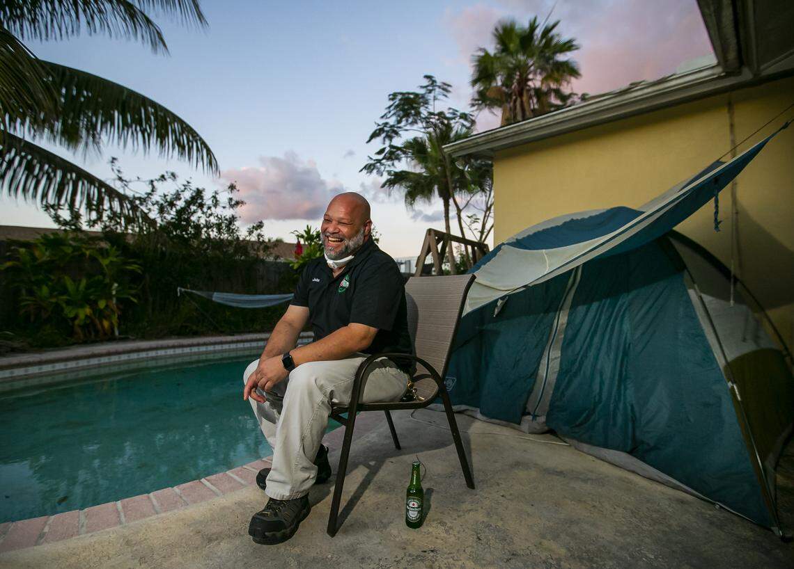 John Delgado, 52, drinks a beer while waiting for nightfall at his home in Homestead, Florida, on Wednesday, April 1, 2020. Delgado, who works at a food bank, opted to stay in a tent in his backyard in an abundance of caution to avoid any possibility of exposing family members to the coronavirus.