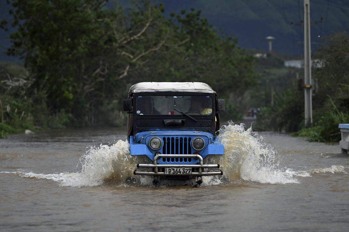 A driver tries to remove his vehicle from a flooded area after heavy rains caused by Hurricane Melissa in the town of San Miguel de Parada, Santiago de Cuba province, on October 29, 2025. A powerful Hurricane Melissa made landfall in eastern Cuba on Wednesday, causing damage and flooding to homes and streets in Santiago de Cuba province, an AFP team on the ground reported. 