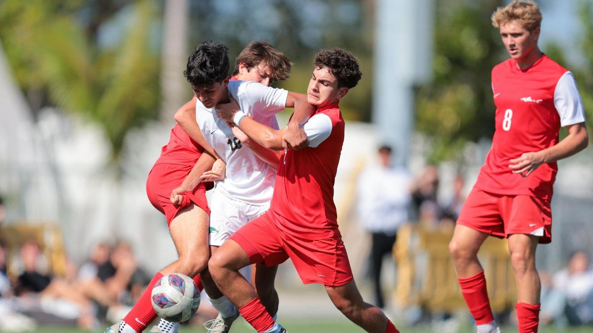 Downtown Doral midfielder Alejandro Avila (18) dribbles the ball past MAST Academy midfielder Jean De Graça (6) and midfielder Felipe Kersting (14) during the second half of a boys soccer Region 4-3A quarterfinal playoff game at MAST Academy in Miami, Florida, Tuesday, February 11, 2025.