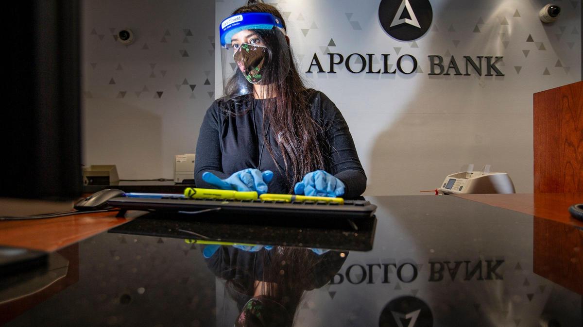 Ashley Torres, relationship banker at Apollo Bank in Miami’s Brickell district, wears a shield and mask to work.
