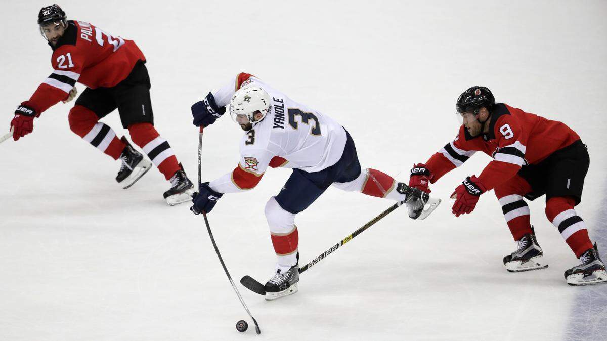 Florida Panthers defenseman Keith Yandle (3) takes a shot as New Jersey Devils right wing Kyle Palmieri (21) and left wing Taylor Hall (9) defend during the third period of an NHL hockey game, Saturday, Oct. 27, 2018, in Newark, N.J. The Devils won 3-2.