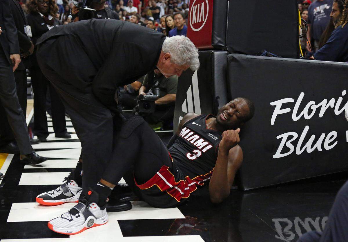 Miami Heat athletic trainer Jay Sabol working with Heat guard Dwyane Wade after a play during the overtime of an NBA basketball game against the Brooklyn Nets at the AmericanAirlines Arena in Miami on Saturday, March 31, 2018.