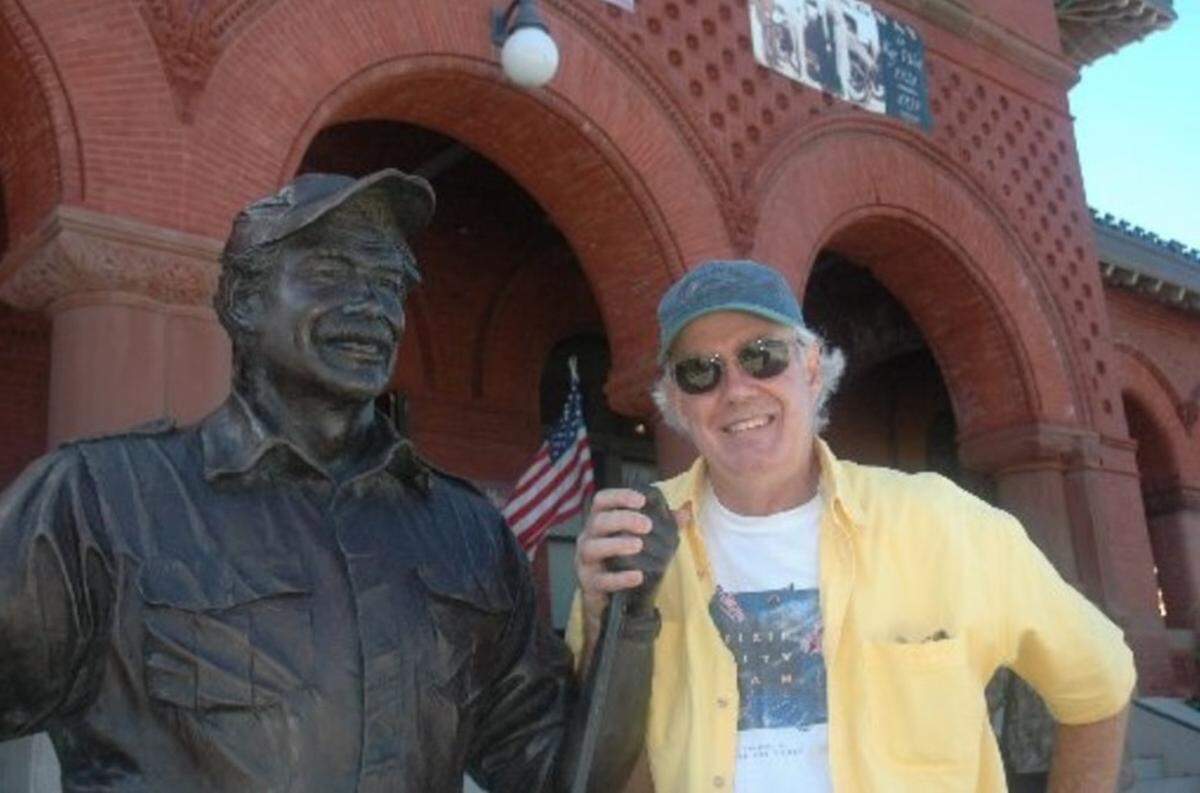 In this file photo from Oct. 30, 2007, author Tom Corcoran poses alongside a bronze statue of Ernest Hemingway in front of the Customs House in Key West. The venue was hosting an exhibit of 70 of Corcoran’s photographs of Key West.