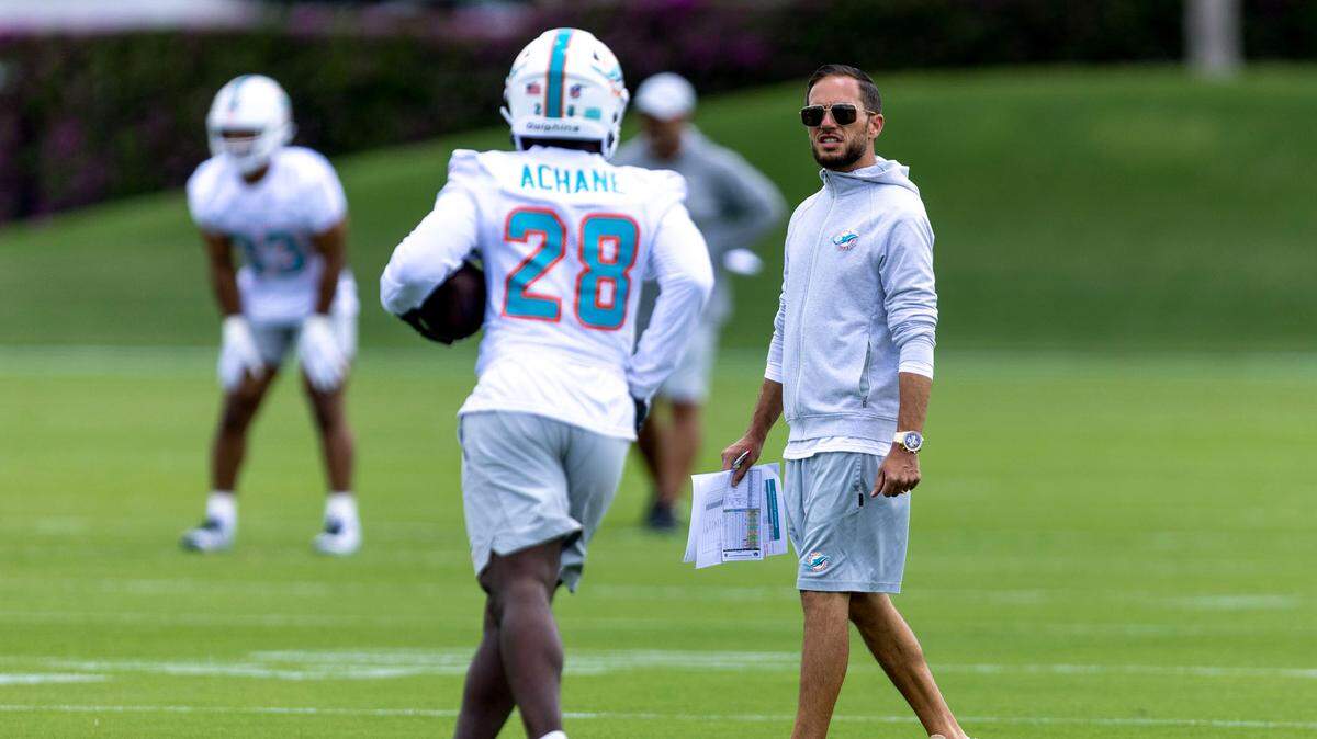 El entrenador de los Dolphins, Mike McDaniel, habla con el running back novato De'Von Achane durante la práctica del minicampamento de verano en el Baptist Health Training Complex, en Miami Gardens, Florida.