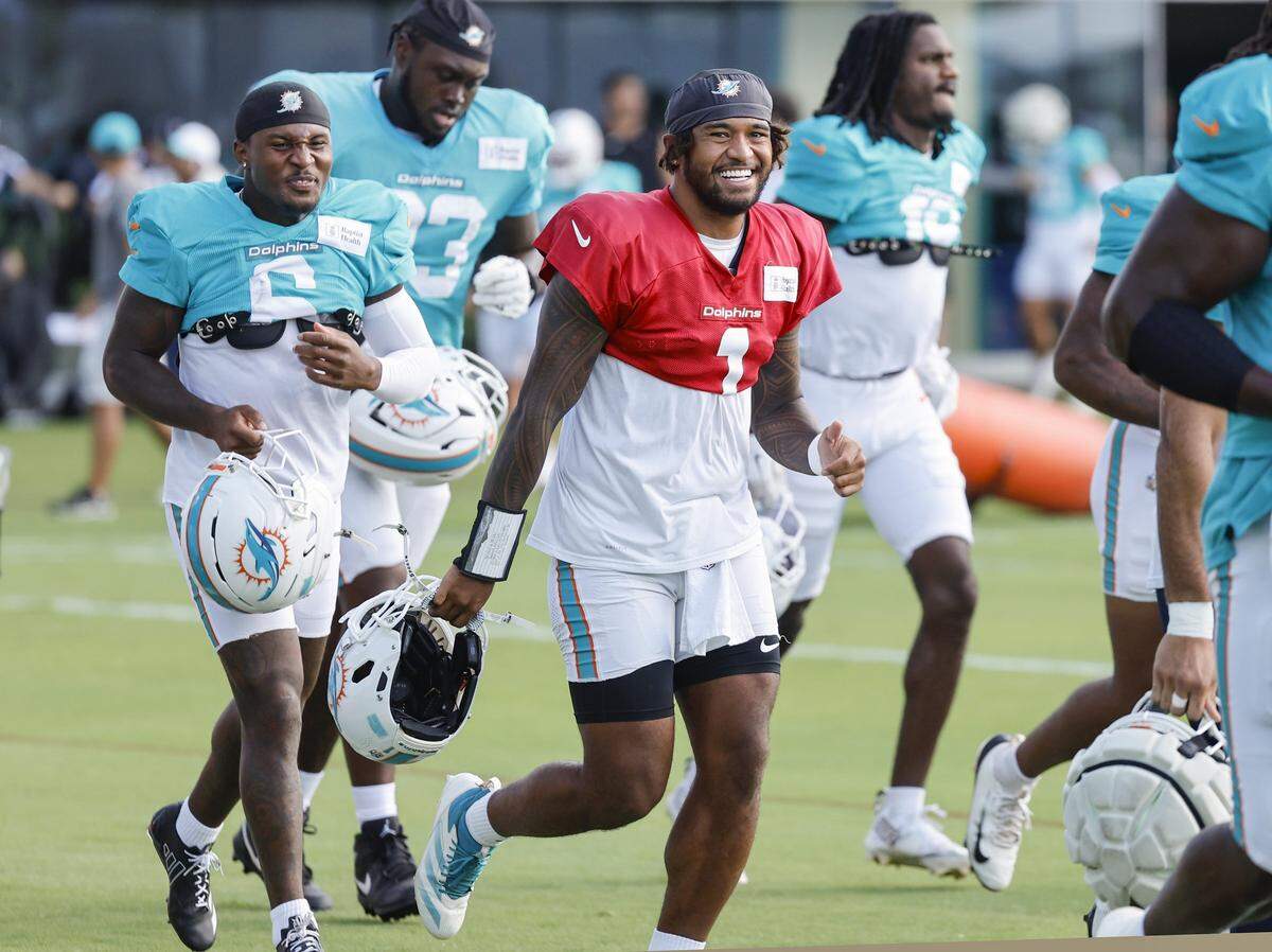 Miami Dolphins quarterback Tua Tagovailoa (1) runs onto the field with teammates before the start of an NFL football joint practice with the Jacksonville Jaguars.