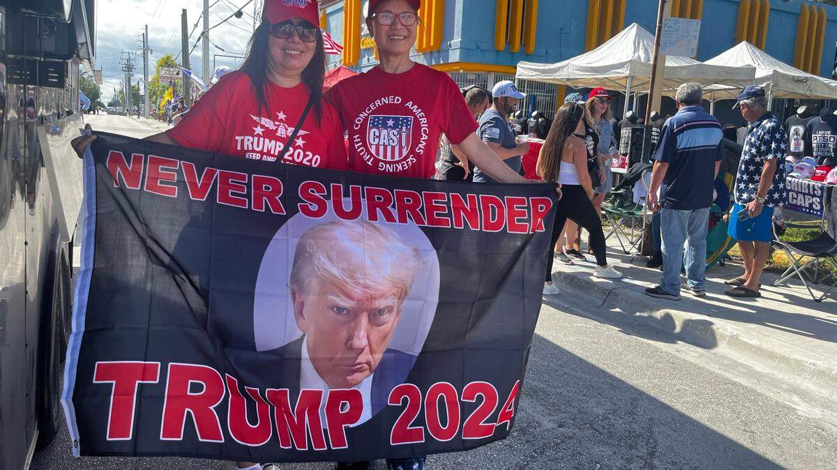 Grace Becker, left, and Hao Hao, 64, hold up a Trump 2024 flag as they await the former president’s rally in Hialeah on Wednesday, November 8, 2023.
