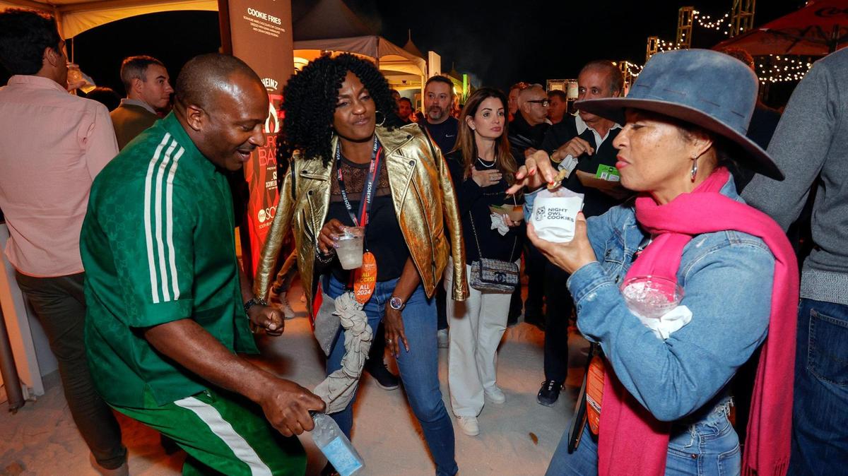 Mark McKenzie and Suzan McDowell dance as Flora Sweet tries out the Night Owl Cookies at the 2024 Burger Bash at the South Beach Wine & Food Festival.