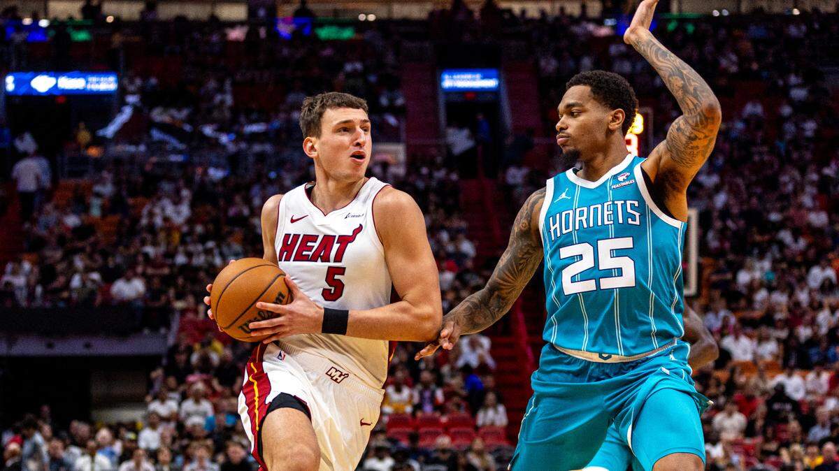 El jugador del Heat Nikola Jovic (izq.) entra al aro ante la marca de P.J. Washington, de los Hornets de Charlotte, en el partido celebrado el 10 de octubre de 2023.