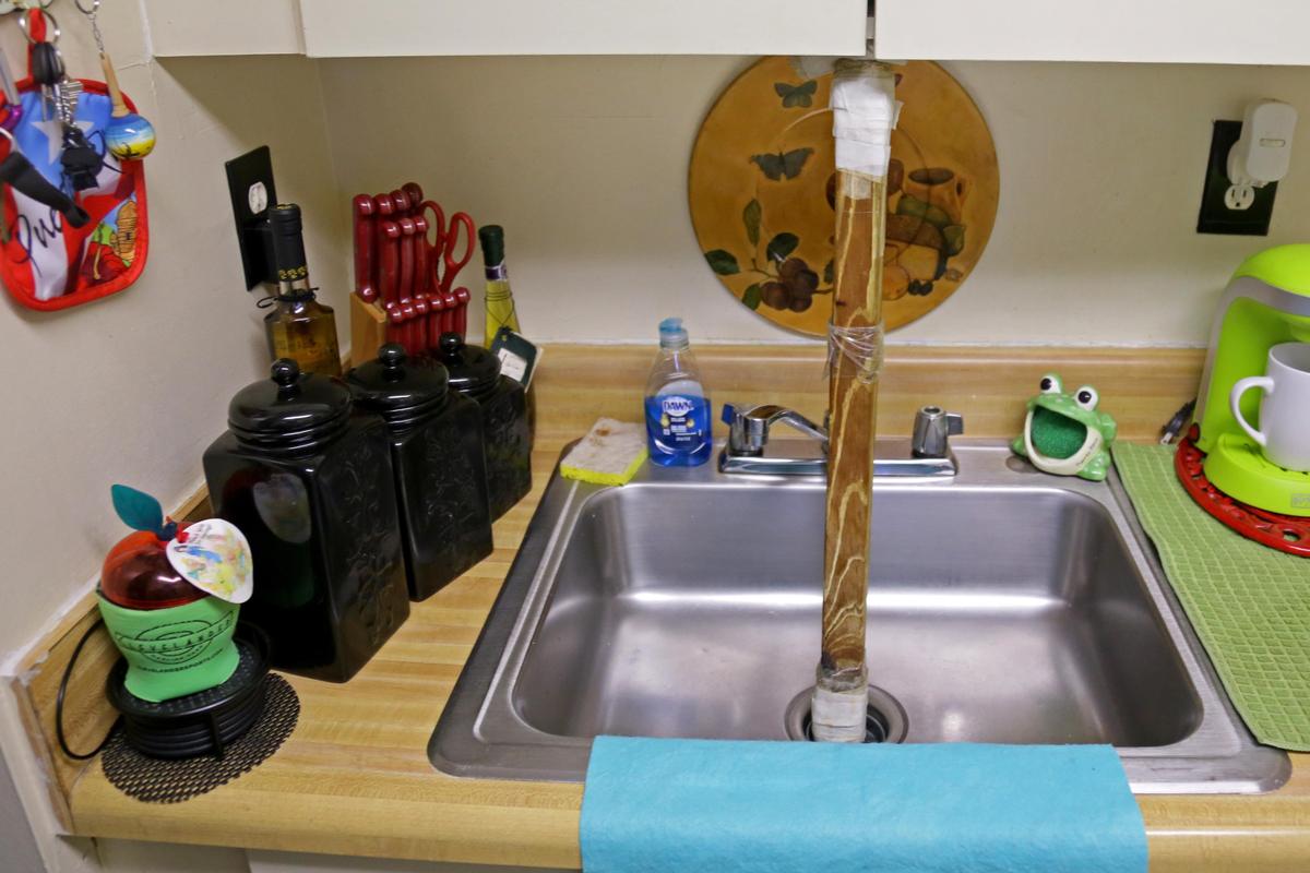 Samuel Cordero, a resident of Harry Cain Tower in downtown Miami, uses a wooden stick in his sink to prevent sewage from coming out and flooding the kitchen.