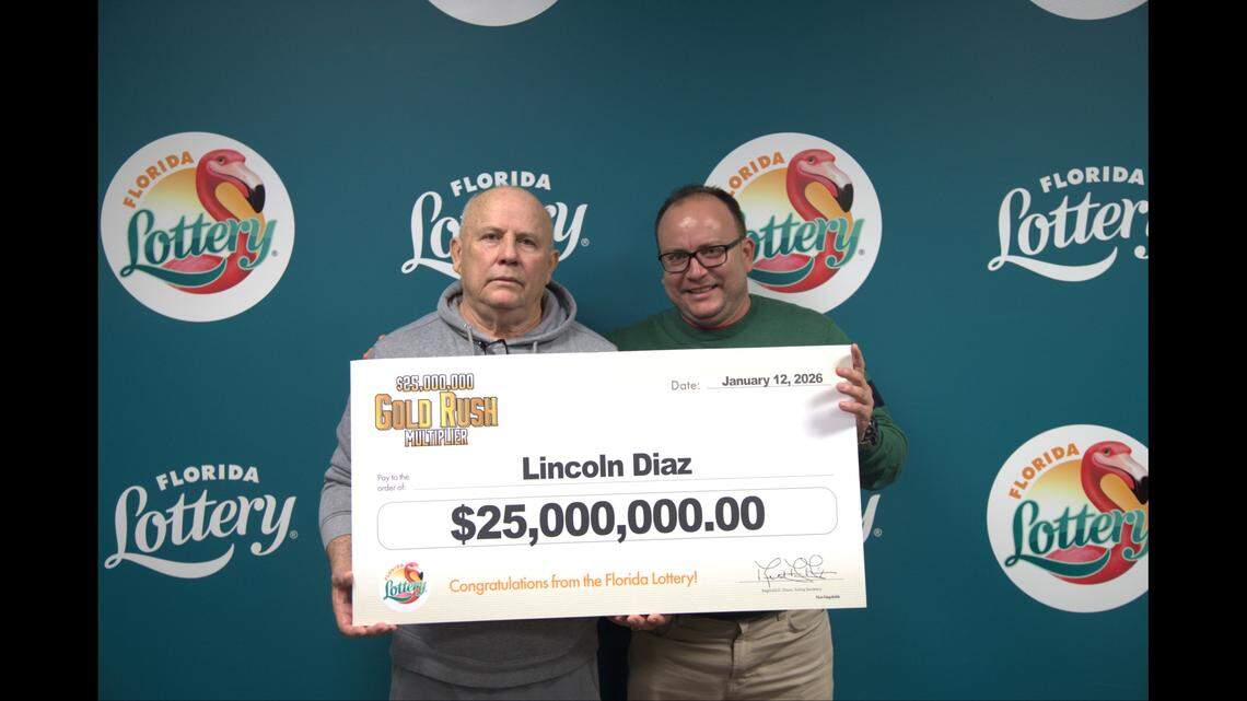 Miami’s Lincoln Diaz, left, holds up the $25 million prize sign with his guest, Alain Diaz, after winning one of the two big prizes in the $25 Million Gold Rush Multiplier scratch off game.