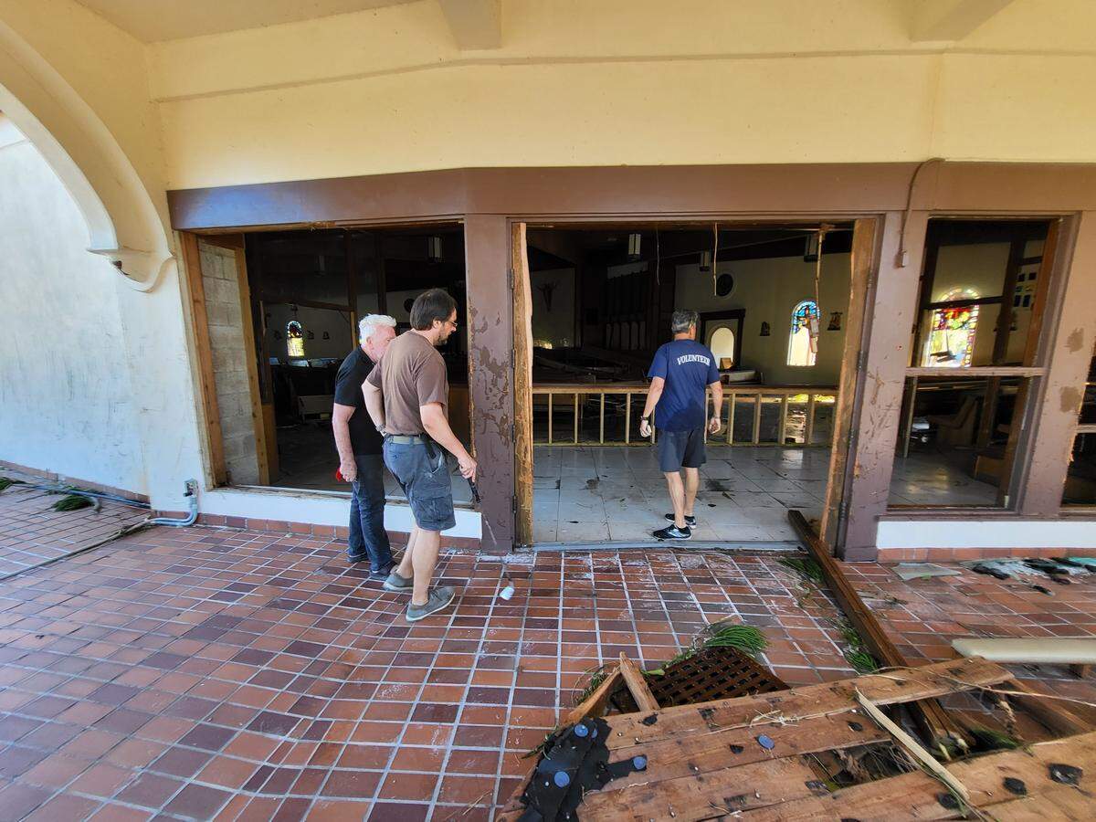 Father William Adams and others survey storm surge damage caused by Hurricane Ian to Ascension Parish church on Fort Myers Beach on Oct. 1, 2022.